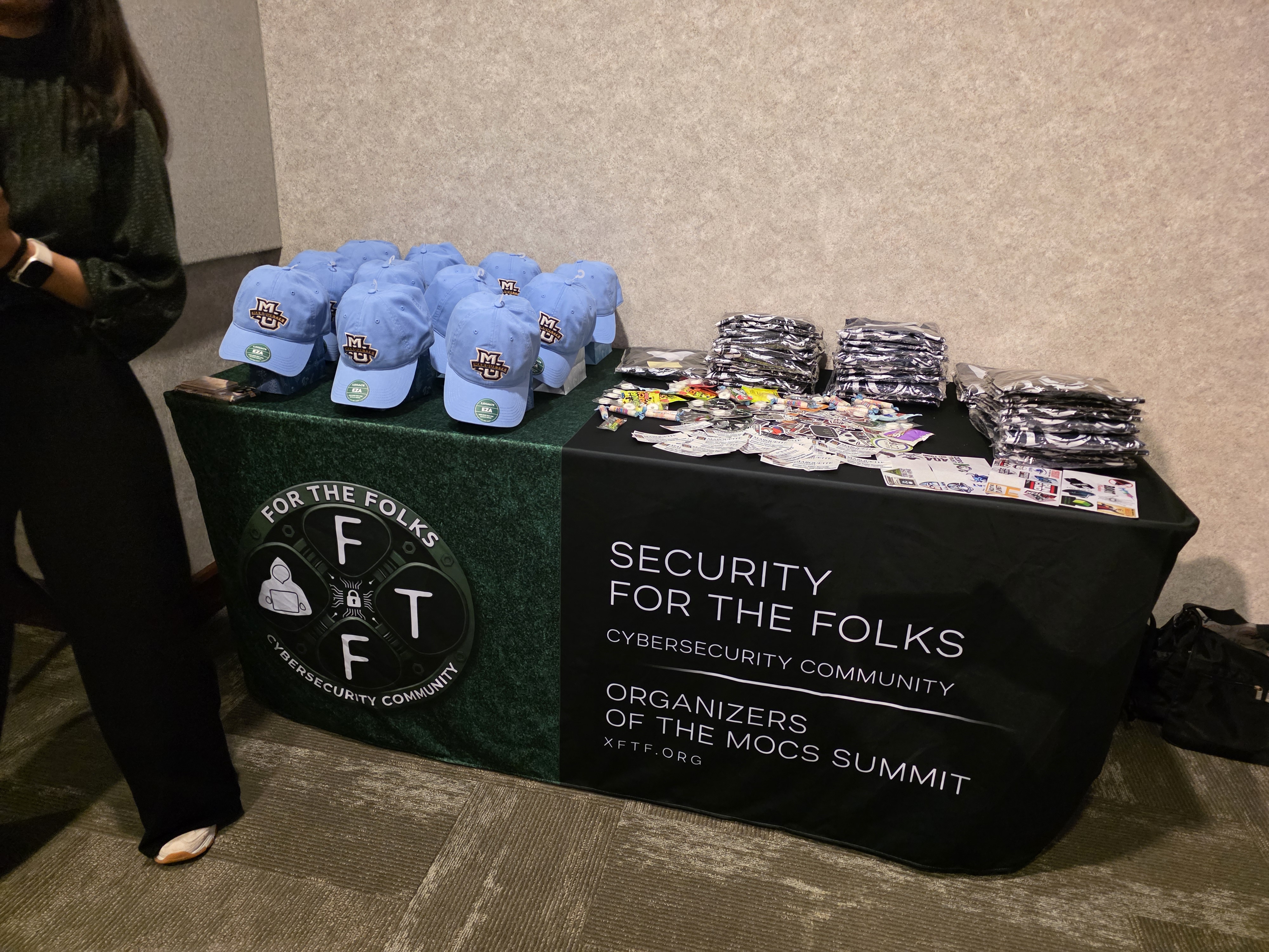 Security For the Folks community table with hats and stickers