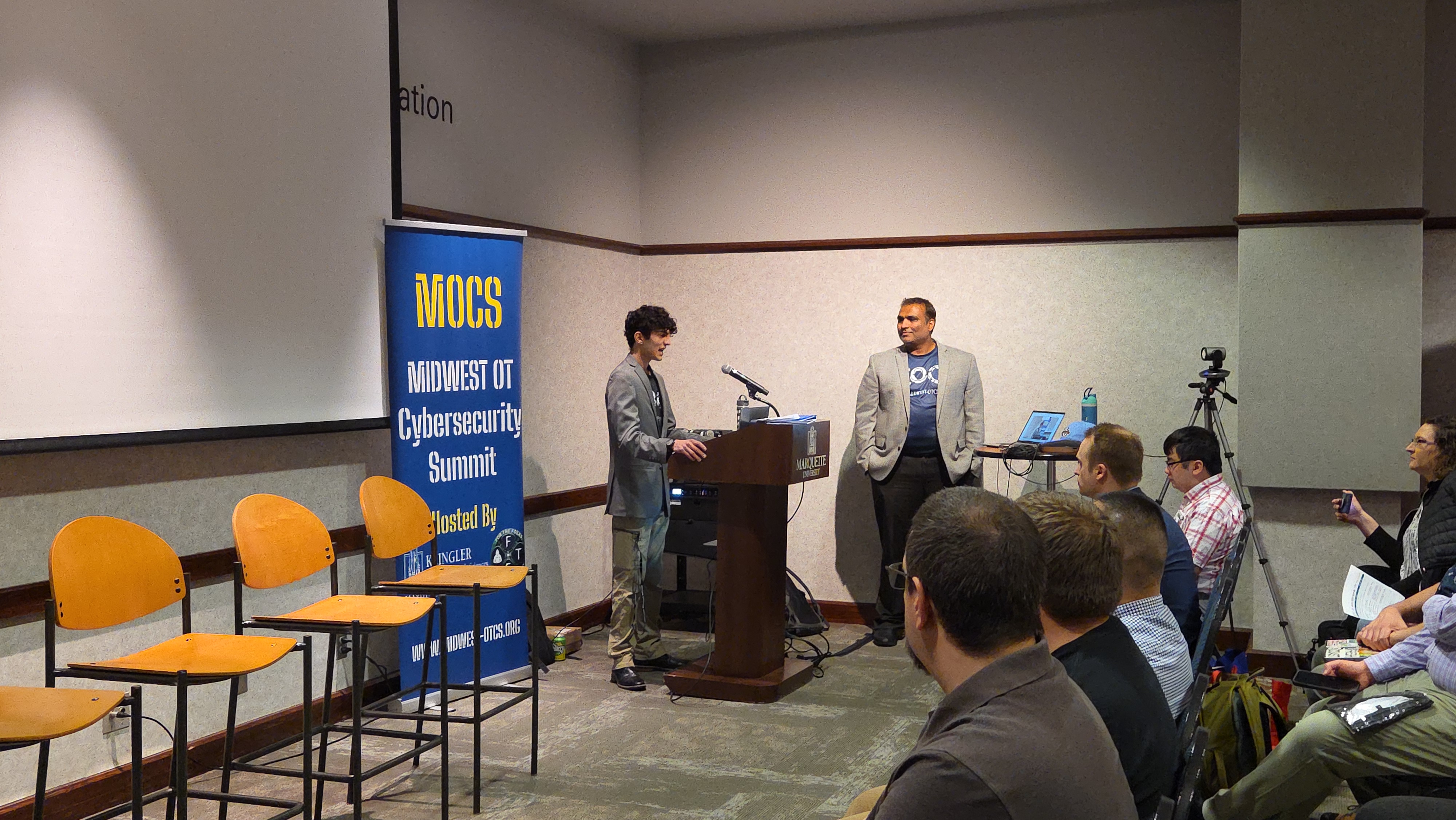 Two presenters opening the conference at the podium