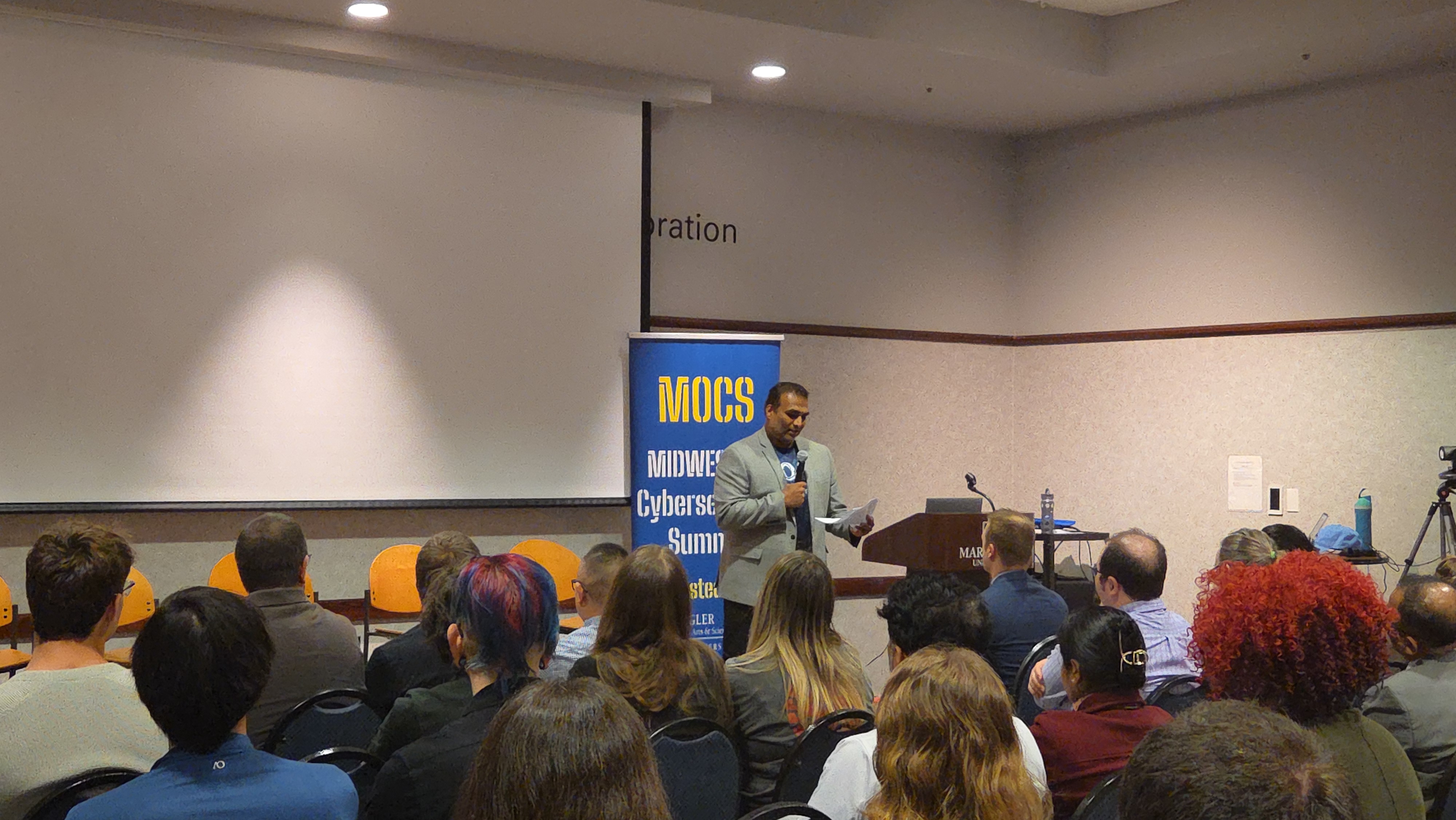 Opening remarks at the podium with MOCS banner