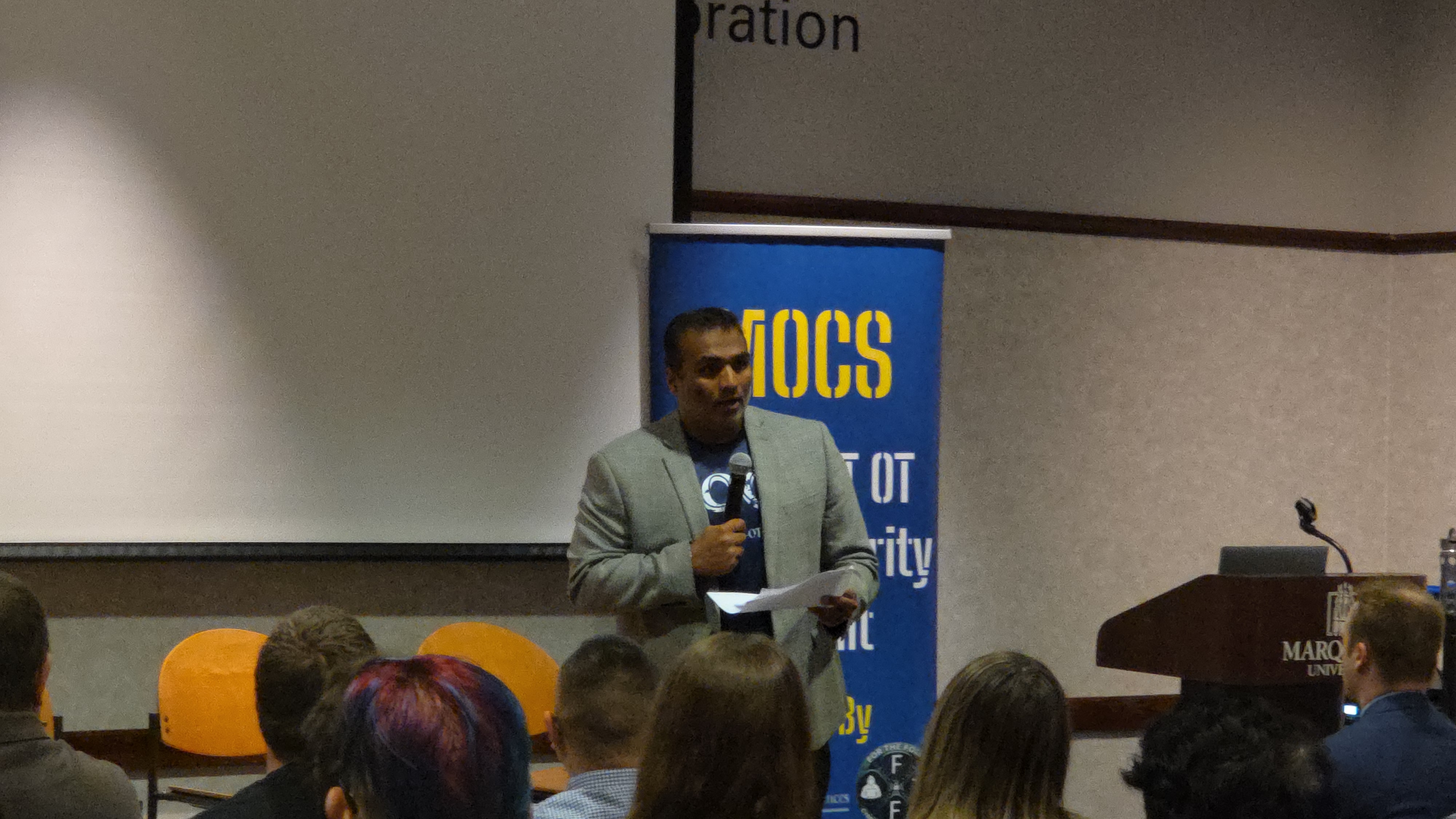 Speaker at the mic with MOCS banner