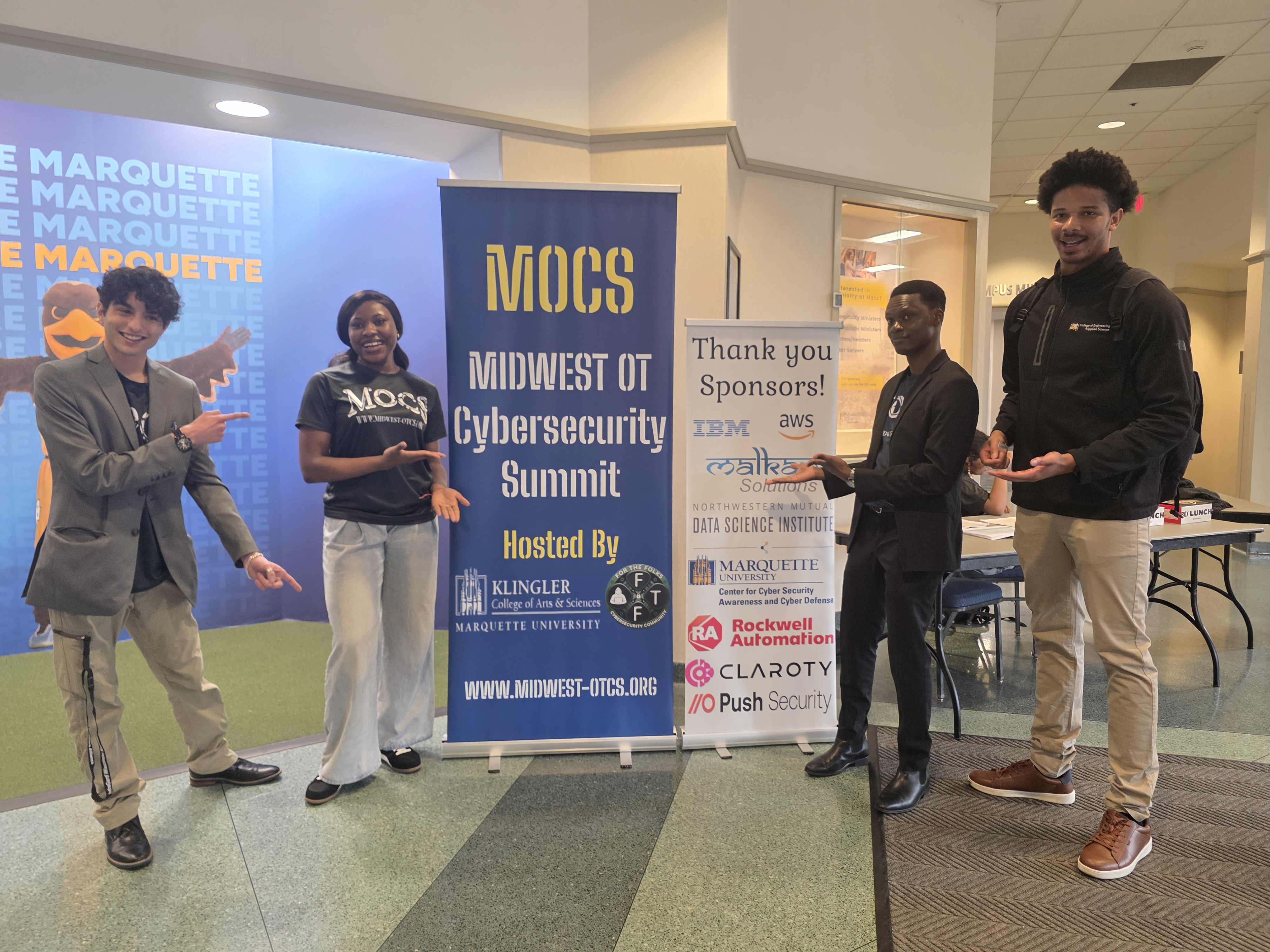 MOCS team and volunteers next to the sponsor banner